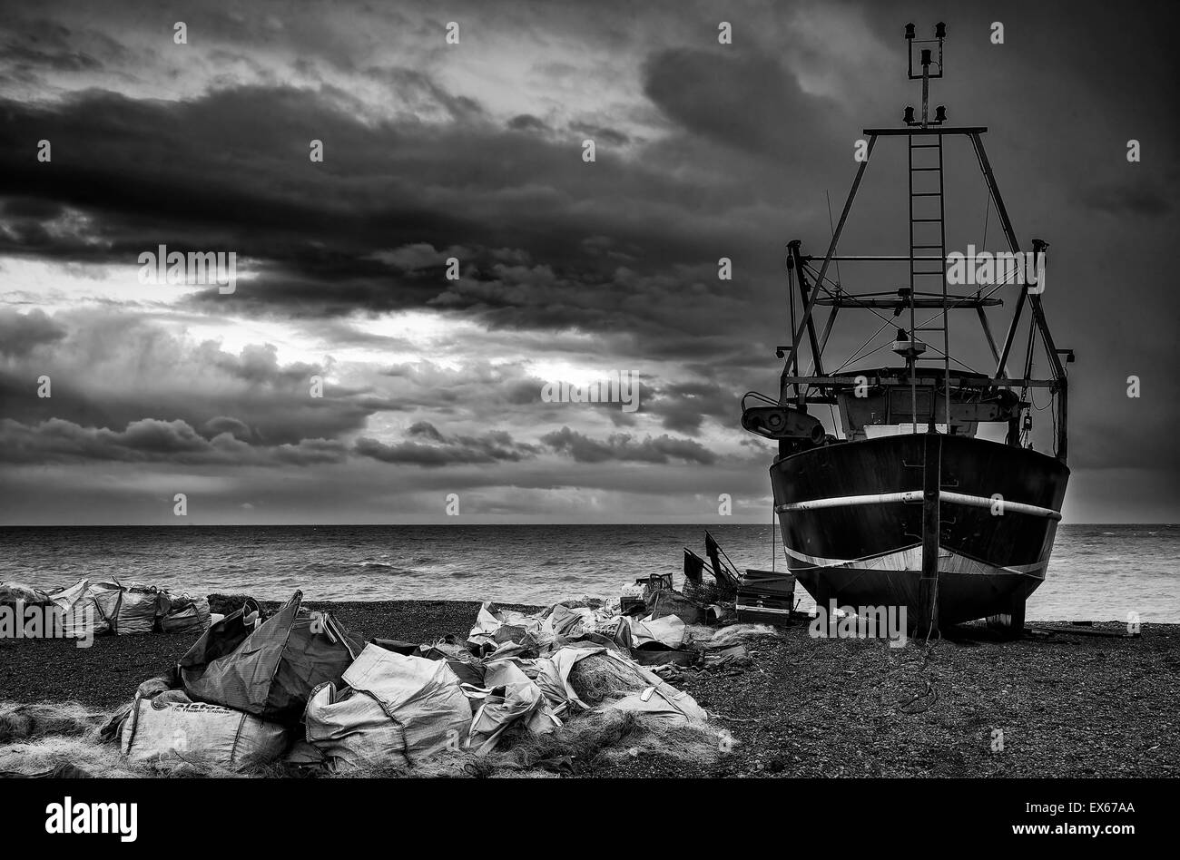 Angelboot/Fischerboot auf Kies Strand Landschaft mit Gewitterhimmel schwarz / weiß Stockfoto
