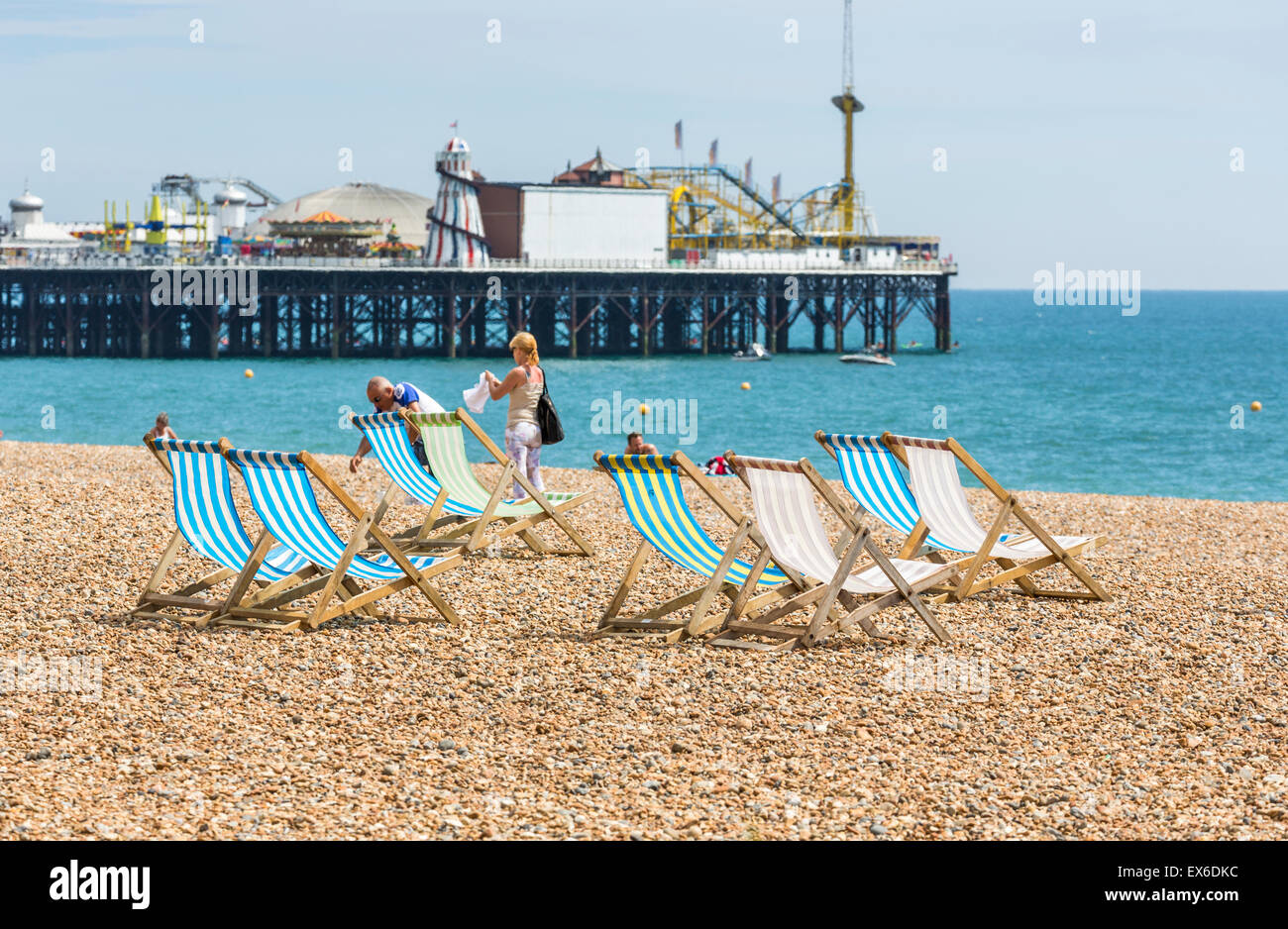 Traditionelle Old-fashioned, leer, blau und weiß gestreifte Liegestühle am Strand, mit Palace Pier, Brighton, East Sussex, UK Stockfoto