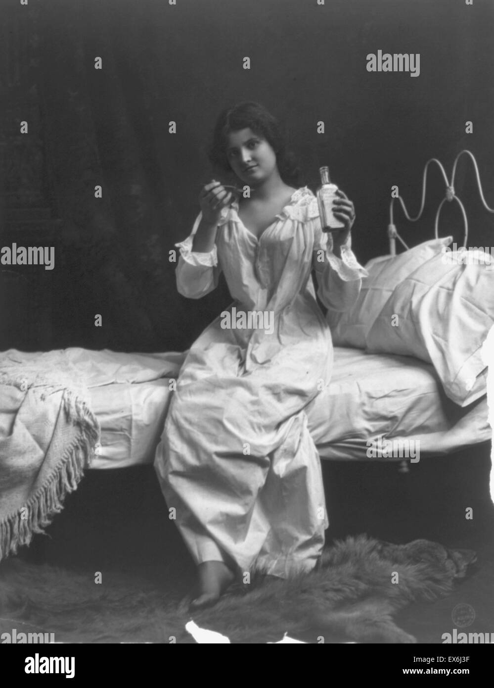 Frau sitzend auf Bett und Löffel Einnahme der Medizin, 1900-10 Stockfoto