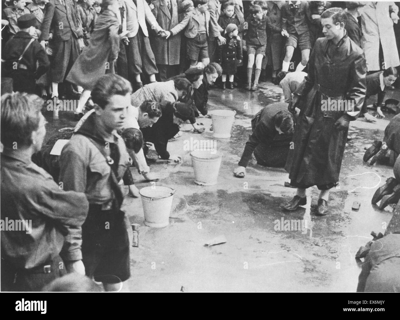 Hitlerjugend (Jugend) Juden zu eine Straße zu reinigen, da eine Menge blickt auf zu zwingen. Wien, Österreich. Datiert 1938 Stockfoto