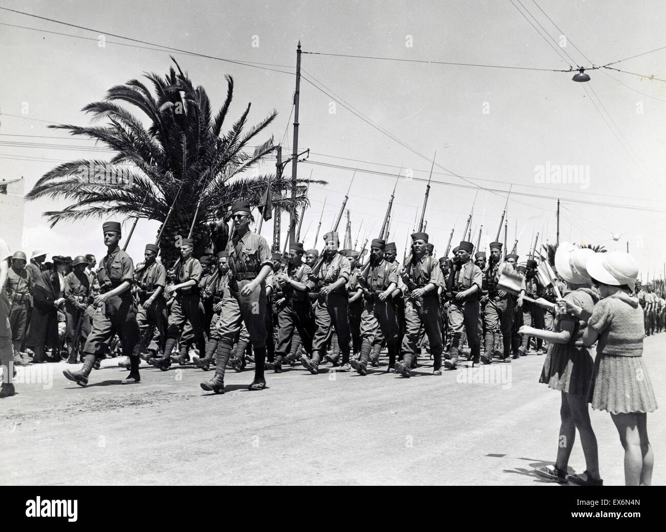 Foto von zwei Kindern, winken, als französische Truppen entlang Avenue Gambetta, während der Sieg der Alliierten Parade, Tunis, Tunesien marschieren. Datiert 1943 Stockfoto