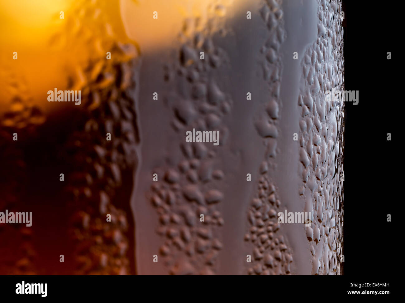 Eine Makroaufnahme von Kondenswasser bilden und ein Glas Tee mit Eis drin auf einem schwarzen Hintergrund tropfte. Stockfoto