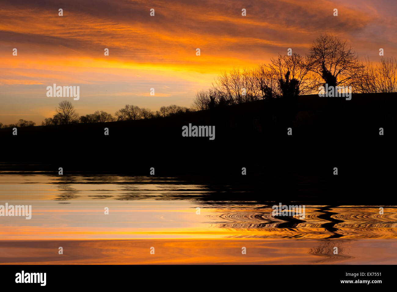 Sonnenuntergang und Bäume spiegeln sich im Plätschern des Wassers Stockfoto