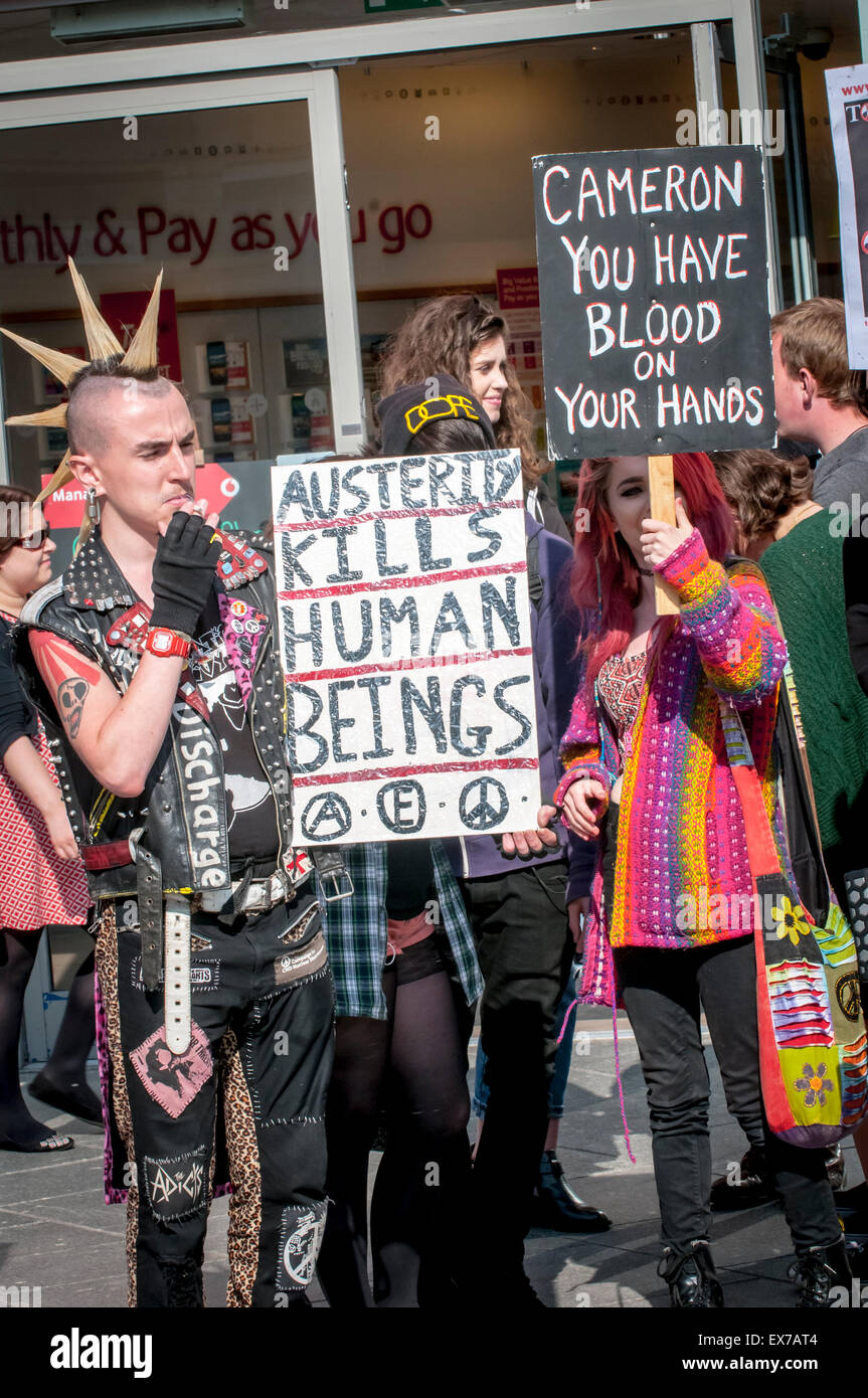 Exeter, Devon, UK. 8. Juli 2015. Ein Mann hält ein Plakat die "Sparmaßnahmen Kils Menschen" sagt und eine Frau hält ein Zeichen, das sagt "Cameron Sie haben Blut an Ihren Händen" bei Exeter-Budget-Aktionstag #AusterityKills in Exeter City Centre am 8. Juli 2015 in Bedford Square, Exeter, UK Credit: Clive Chilvers/Alamy Live News Stockfoto