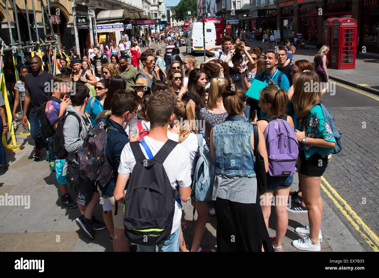 Sommer in London, England, Vereinigtes Königreich. Massen von Touristen und Käufer treffen sich in Leicester Square. Dies bleibt eine der Londoner Tourismus Hotspots mit Entertainer und Shop und Raum zu hängen. Es gibt eine riesige Anzahl von Student Reisegruppen, die in Massen bewegen. Stockfoto
