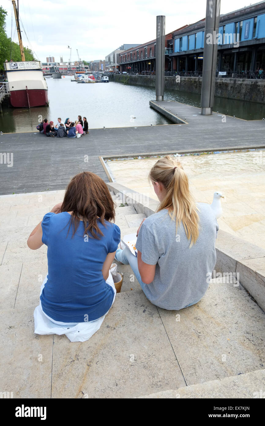 Zwei junge Frauen sitzen auf der Treppe neben dem Wasserspiel im Harbourside Bristol, 8. Juli 2015 Stockfoto