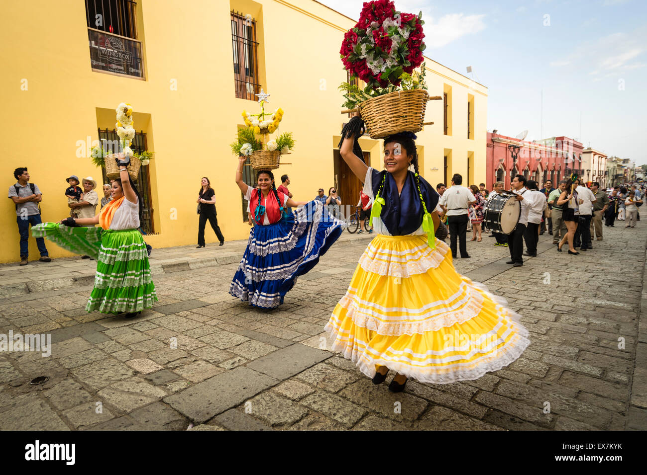 Frauen in traditionellen Kostümen tanzen und Durchführung Blumenkörbe auf ihren Köpfen führt eine Parade auf einem Festival in Oaxaca, Mexiko Stockfoto