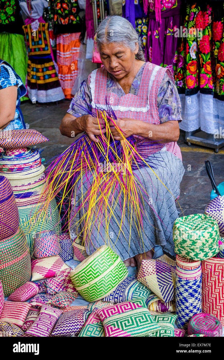 Alte Frau macht traditionelle geflochtene Körbe aus bunten Kunststoff-Streifen in einem Markte in Oaxaca, Mexiko Stockfoto