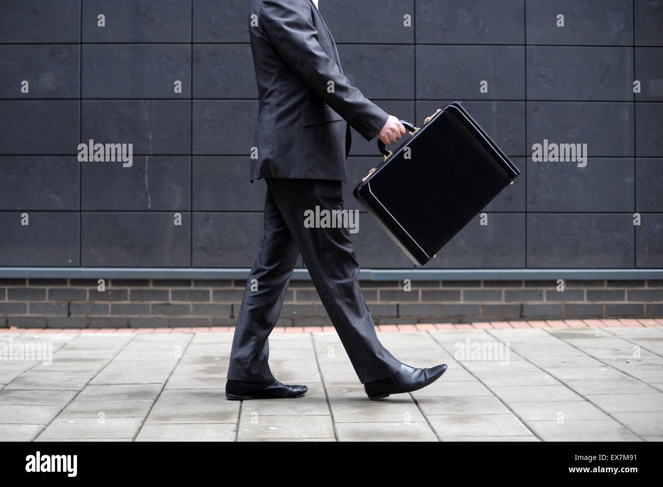 Ein Business-Mann trägt einen Aktenkoffer auf dem Weg zur Arbeit in einem Büro. Stockfoto