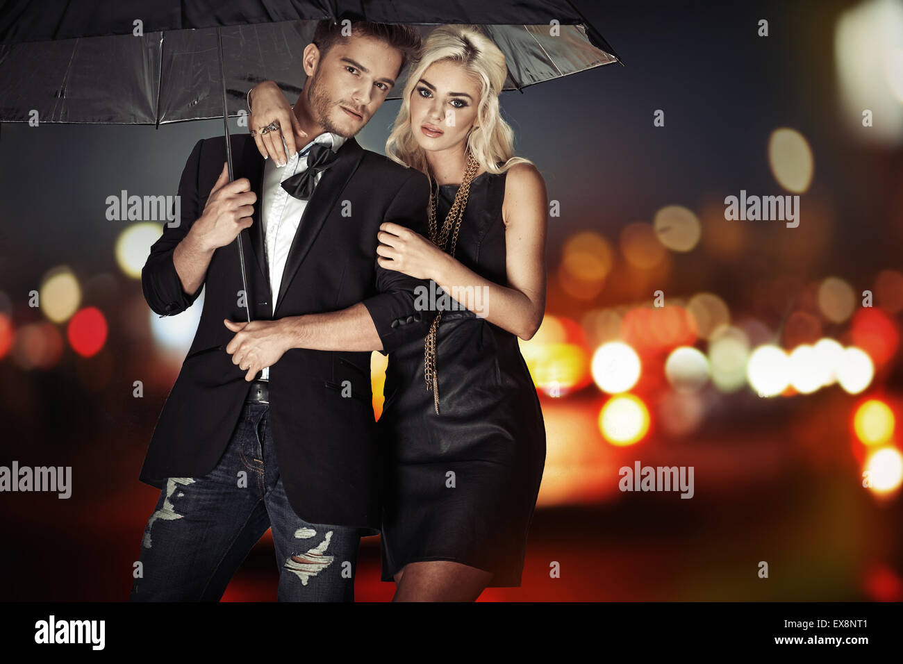 Intelligente Paare, die mit dem schwarzen Regenschirm Stockfoto