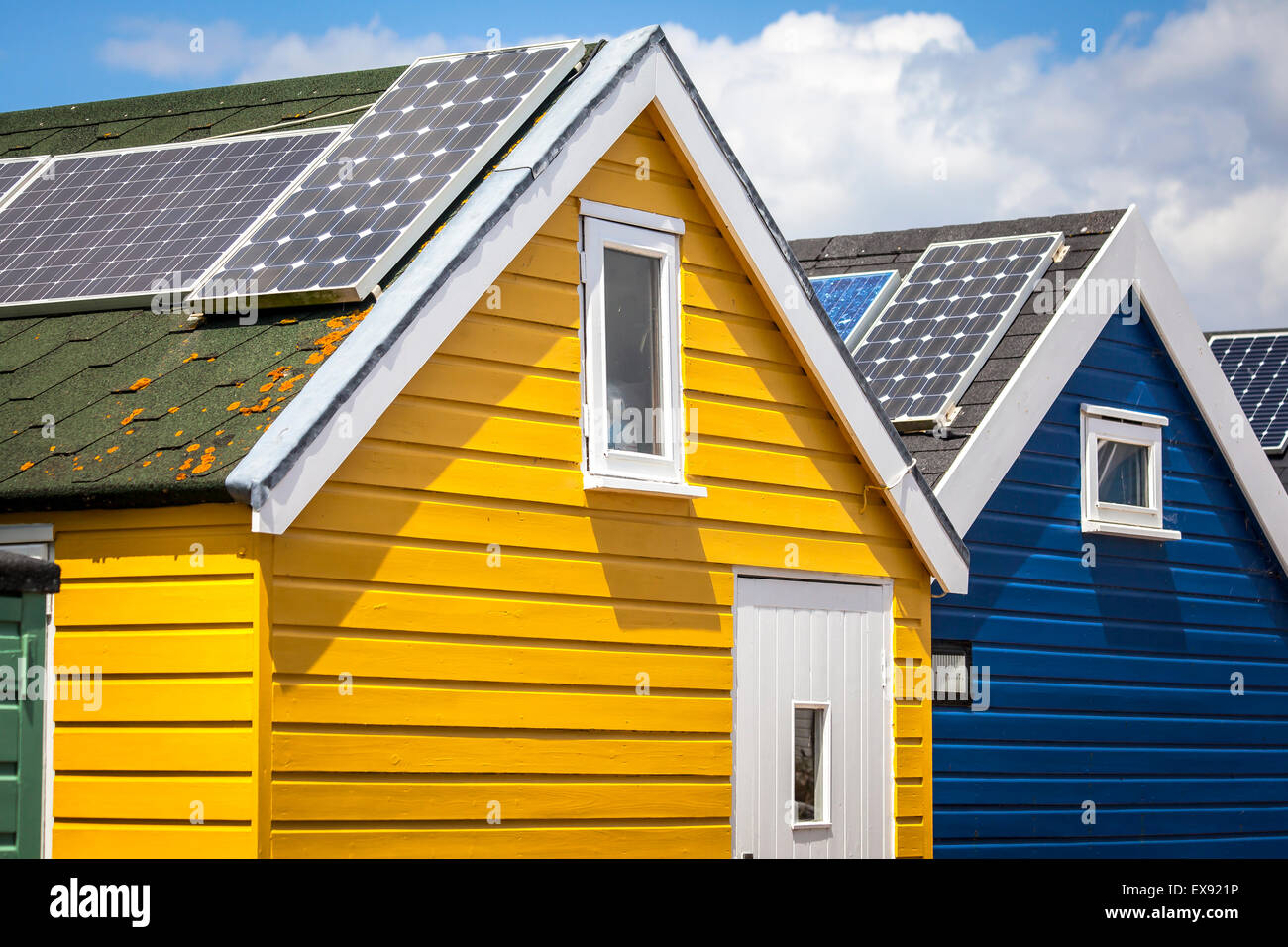 Bunt bemalten Strandhütten auf der Küste von Dorset mit Solarzellen auf den Dächern Stockfoto