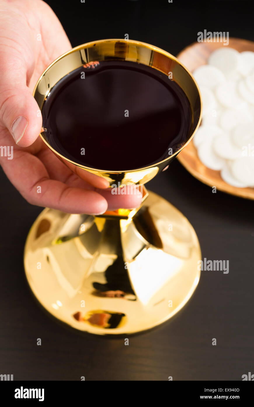 Christliche Heilige Kommunion, Mannes Hand halten gold Kelch mit Wein, Hostie auf Platte Stockfoto