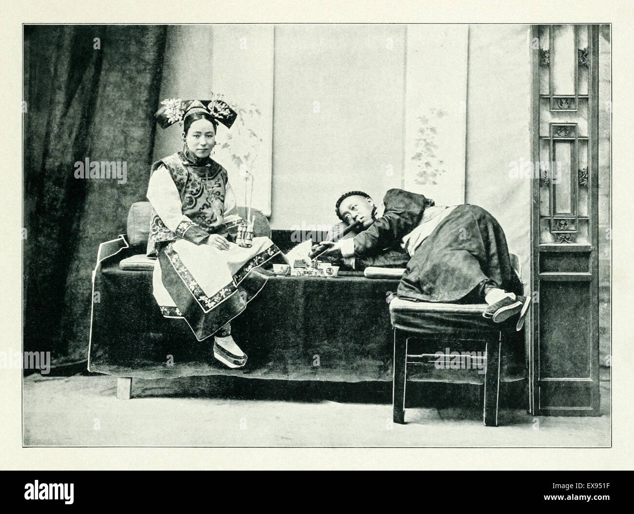 Ein chinesischer Mann Rauchen von Opium in Peking (heute Beijing) mit einem Begleiter hält eine Tabakpfeife circa 1905, aus einem Fotoalbum von Peking produziert für den Tourismus und 1906 veröffentlicht. Stockfoto