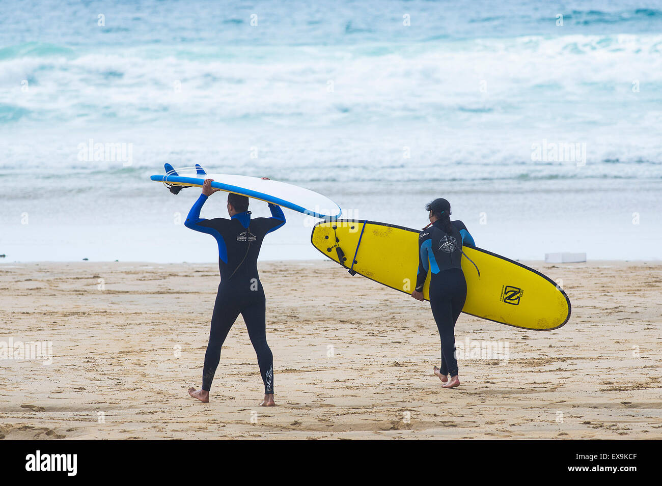 Surfer tragen ihre Surfbretter, wie sie zum Meer am Fistral Beach in Newquay, Cornwall Fuß. Stockfoto