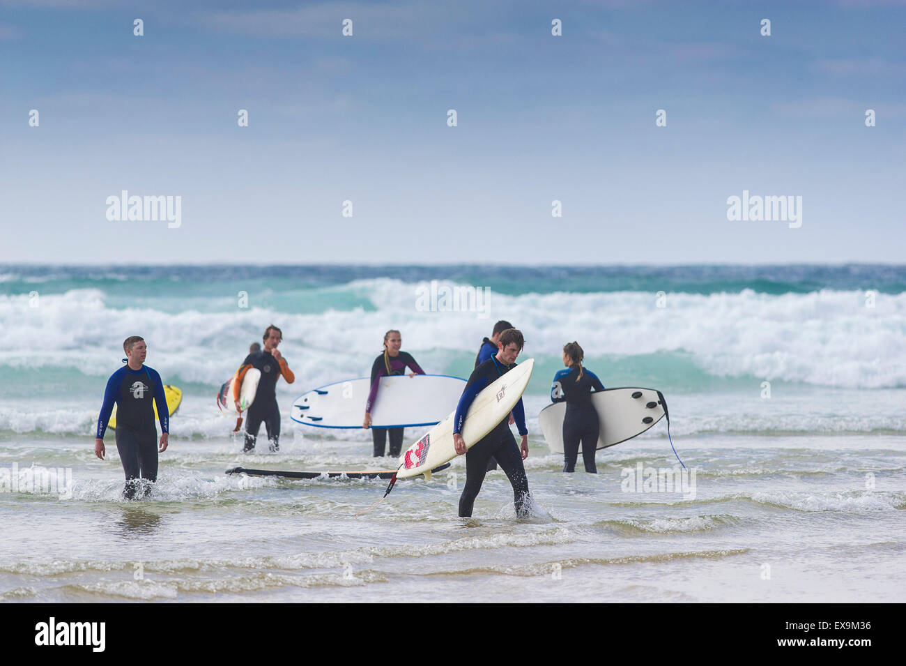 Eine Gruppe von Surfern Fuß aus dem Meer am Fistral Beach in Newquay, Cornwall. Stockfoto