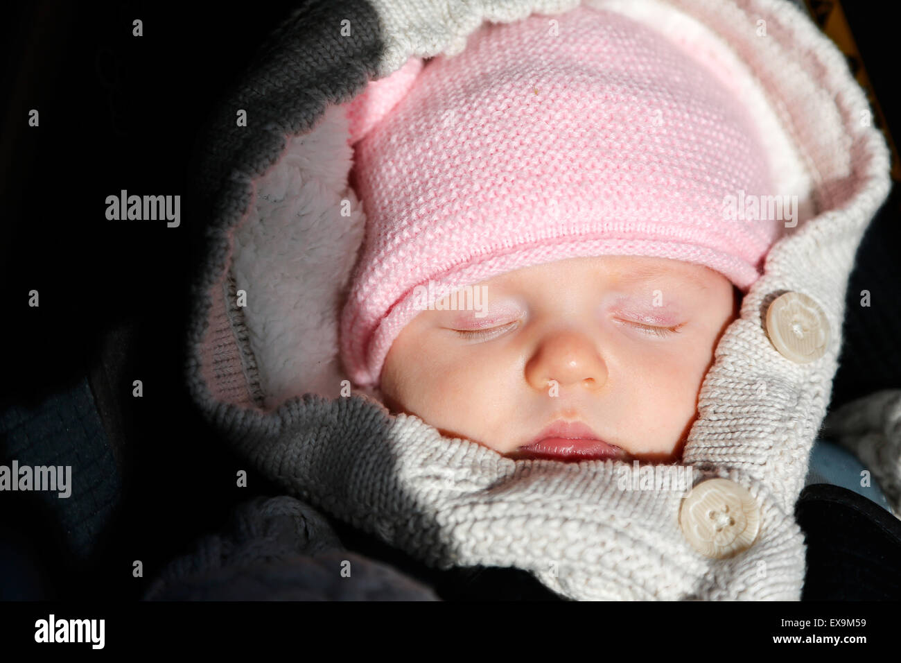 Ein Baby, eingewickelt in warme Winterkleidung, gemütlich und in ihrem Kinderwagen, trotz des kalten englischen Winters Stockfoto