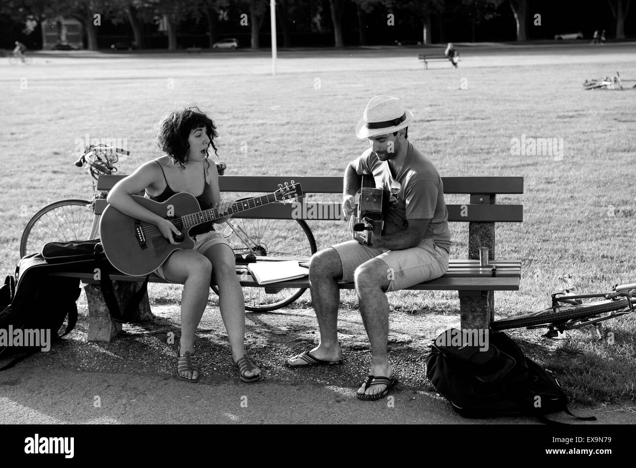 Paar Duett singen & spielen Gitarre Gitarren auf öffentlichen Parkbank in Annecy, Frankreich Stockfoto