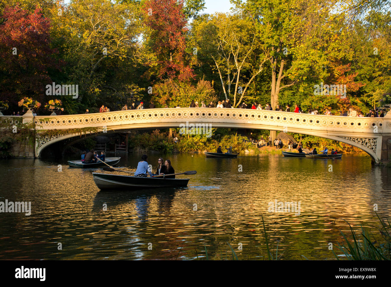 Menschen im See Bootfahren und betrachten der Szene über Bogen-Brücke an einem Herbstabend im Central Park in New York City Stockfoto