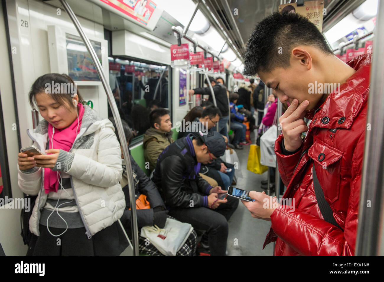 China, Shanghai, junge Erwachsene SMS und spielen auf dem Handy an Bord Shanghai Metro u-Bahn Stockfoto