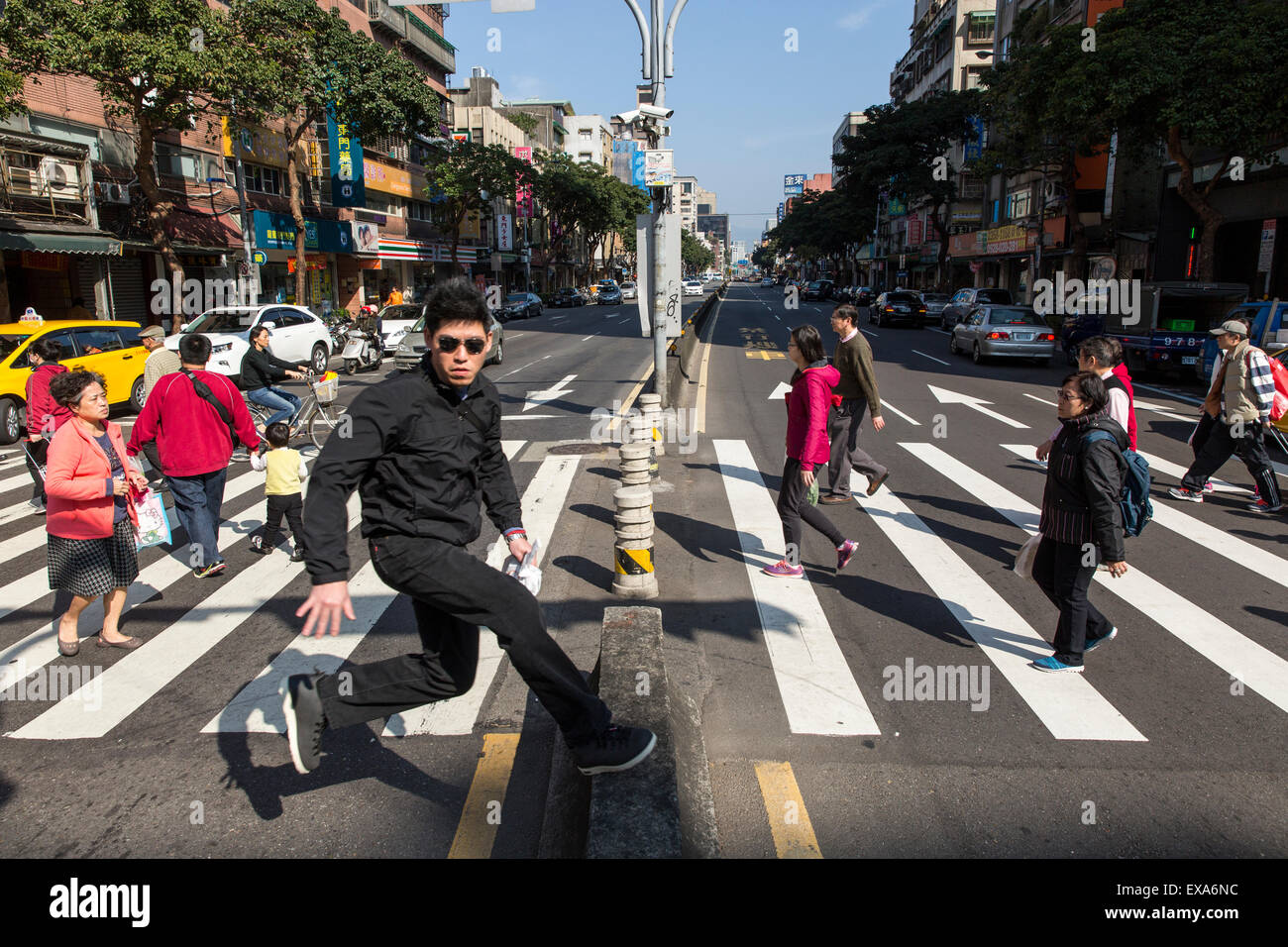 Asien, Taiwan, Taipei, junger Mann springt über Zentrum Schranke Vergangenheit drängen sich zu Fuß auf Zebrastreifen in der Nähe von Dongmen-Markt auf sonnigen alle Stockfoto