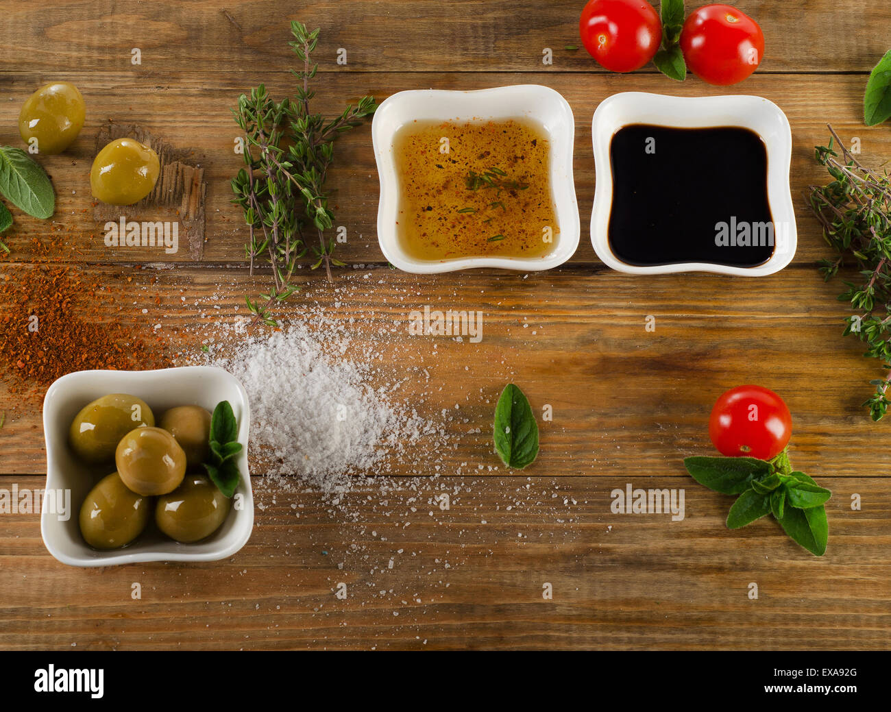 Dressing Zutaten auf einem rustikalen hölzernen Hintergrund. Olivenöl, Balsamico-Essig, Kräuter, Salz und Pfeffer. Ansicht von oben Stockfoto