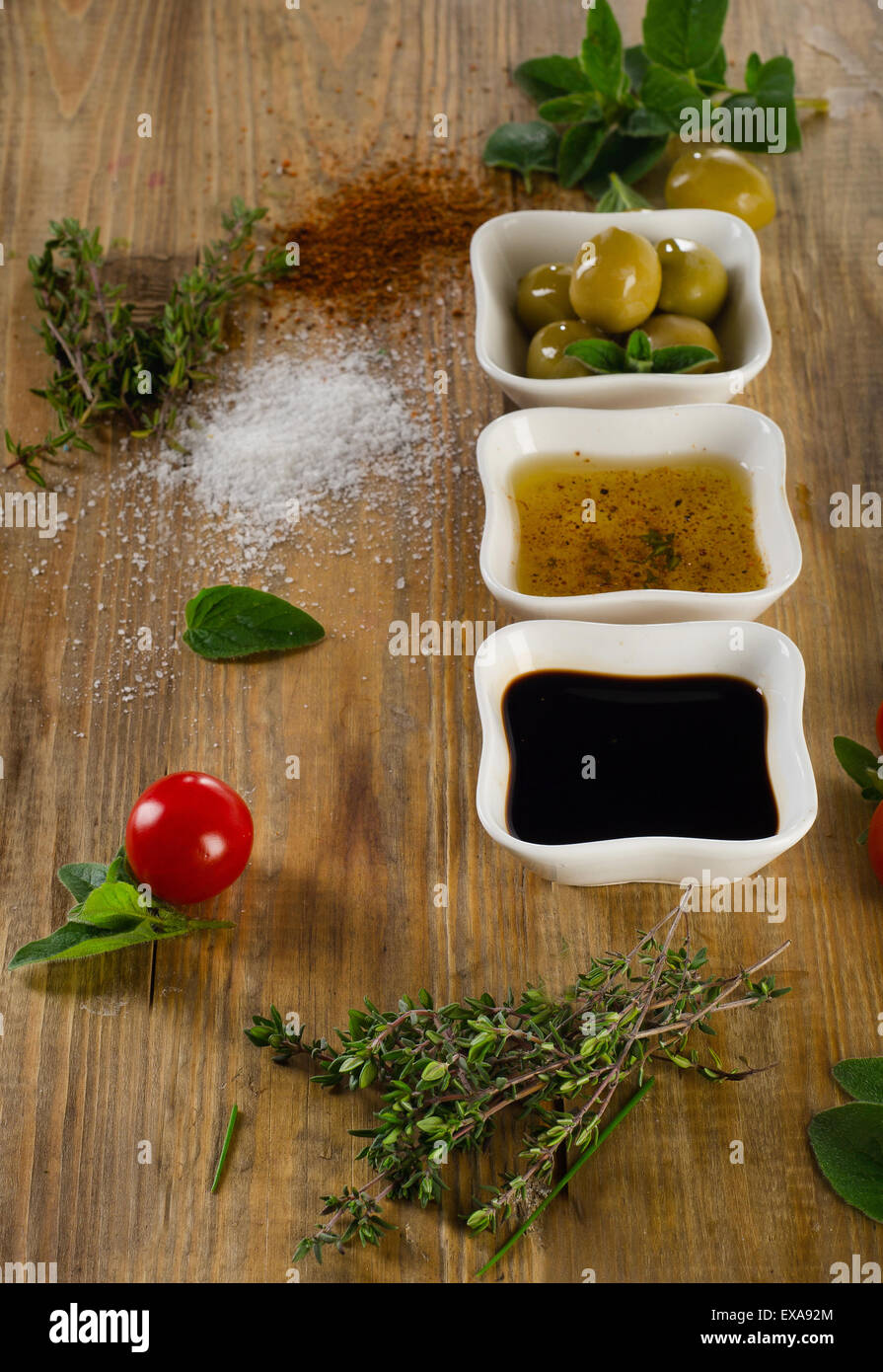 Dressing Zutaten auf einem rustikalen hölzernen Hintergrund. Olivenöl, Balsamico-Essig, Kräuter, Salz und Pfeffer. Selektiven Fokus Stockfoto