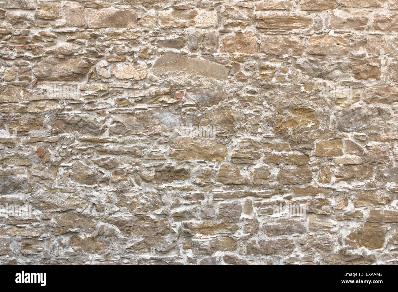 Alte Mauer bestehend aus unregelmässigen Steinen mit warmen Farben. Stockfoto