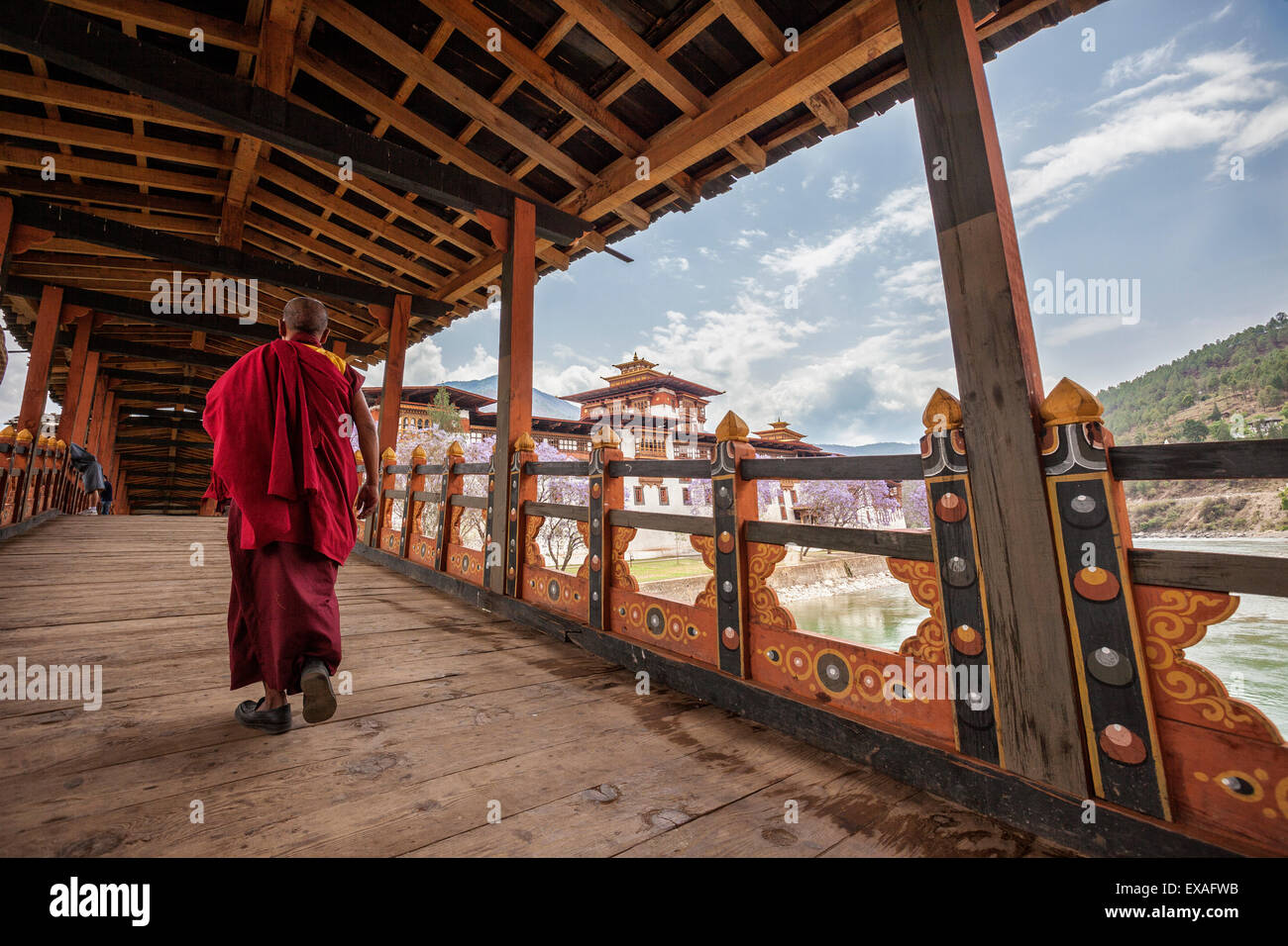 Ein Mönch (Lama) von Punakha Dzong kreuzt die hölzerne Brücke über den Fluss, die Zugang zu dem alten Kloster, Bhutan Stockfoto