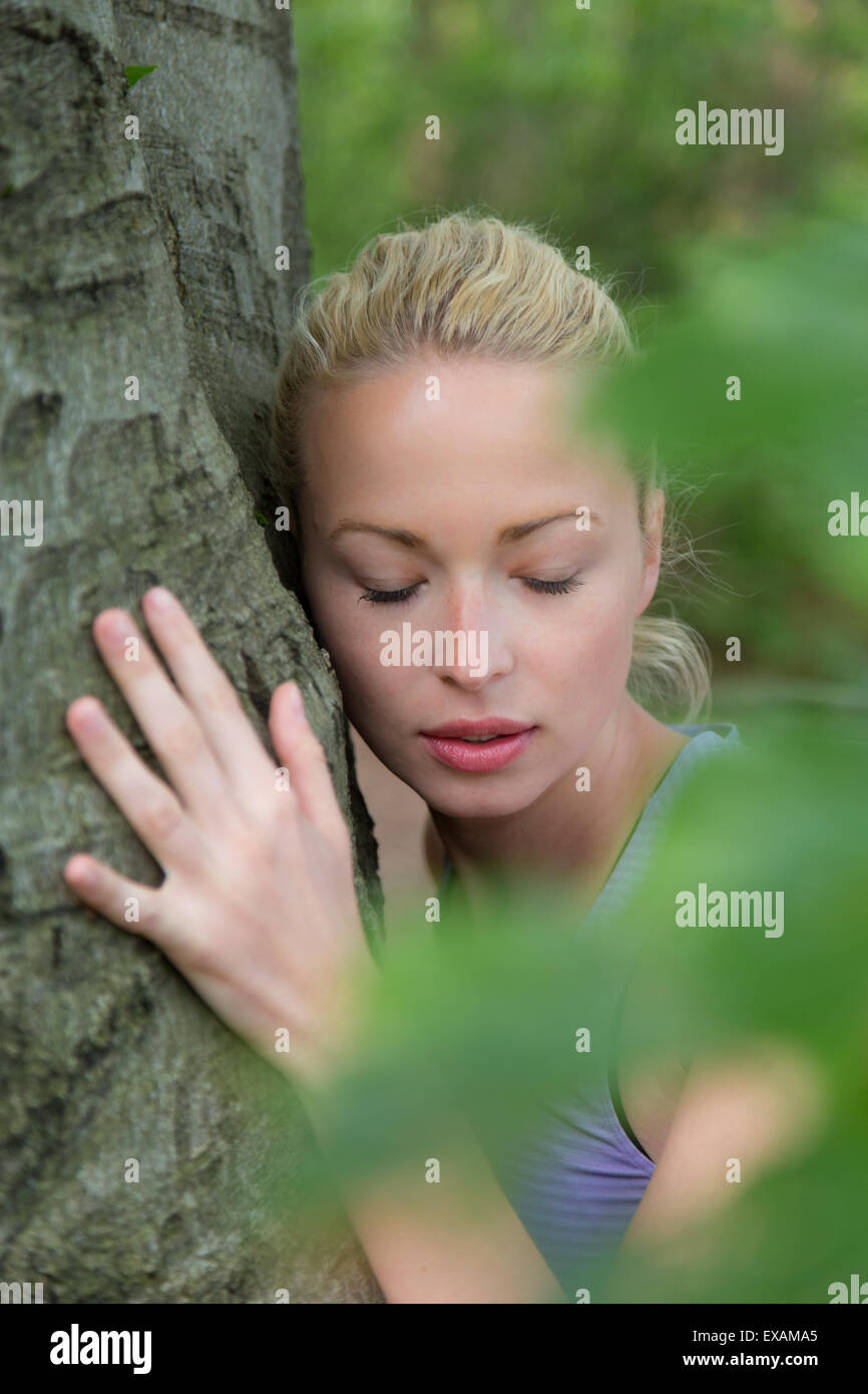 Junge Frau umarmt einen Baum. Stockfoto