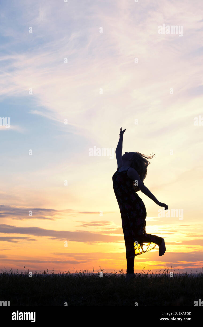 Teenager-Mädchen energetisch Spaß bei Sonnenuntergang herumspringen. Silhouette Stockfoto