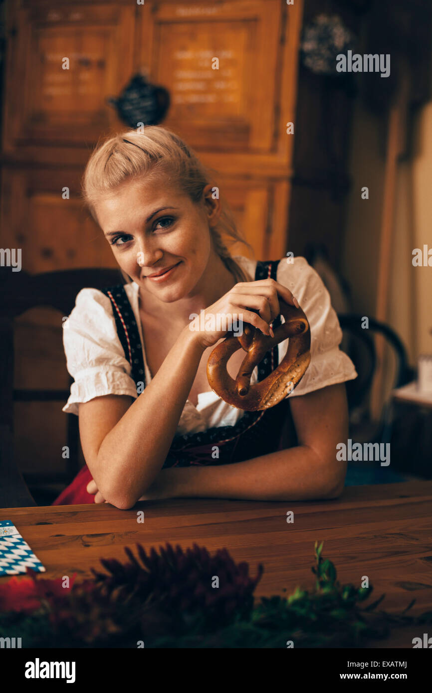 Frau sitzt am Tisch mit Maß Bier und Brezel Stockfoto