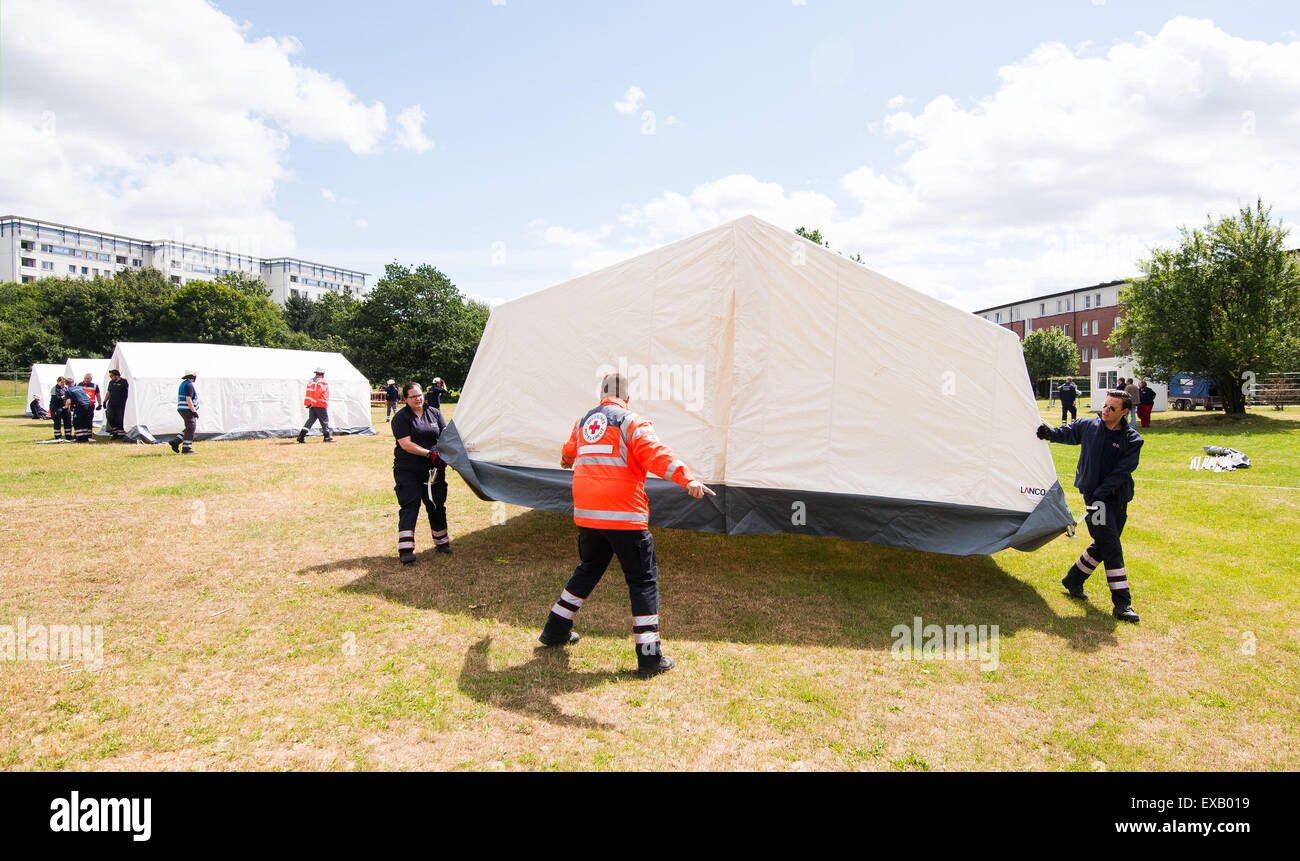 Hamburg, Deutschland. 10. Juli 2015. Helfer vom DRK (Deutsches Rotes Kreuz)  tragen ein Zelt auf eine neue Unterkunft Flüchtlingszentrum in Hamburg,  Deutschland, 10. Juli 2015. Die Stadt Hamburg wurden gezwungen, aufgrund der