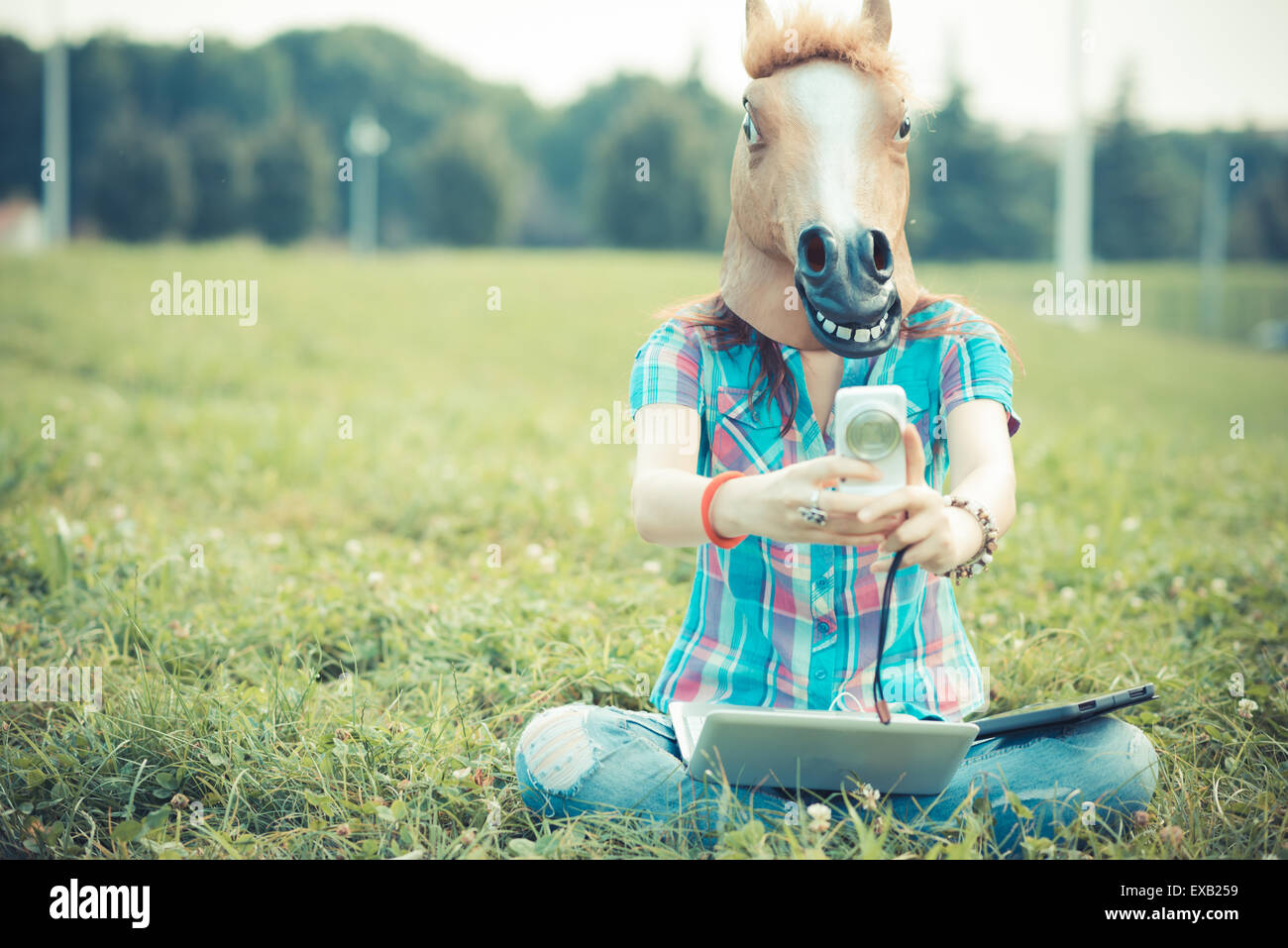 Pferd Maske unwirklich Hipster Frau mit Technologie im park Stockfoto