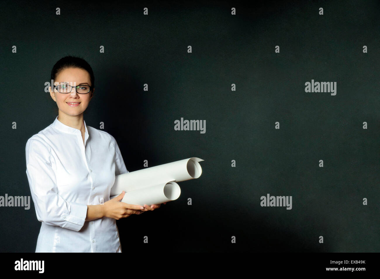 Studio-Porträt einer Ingenieur-Frau in eine weiße Bluse mit einem Stack von Zeichnungen, dunklen Hintergrund mit Leerzeichen Stockfoto