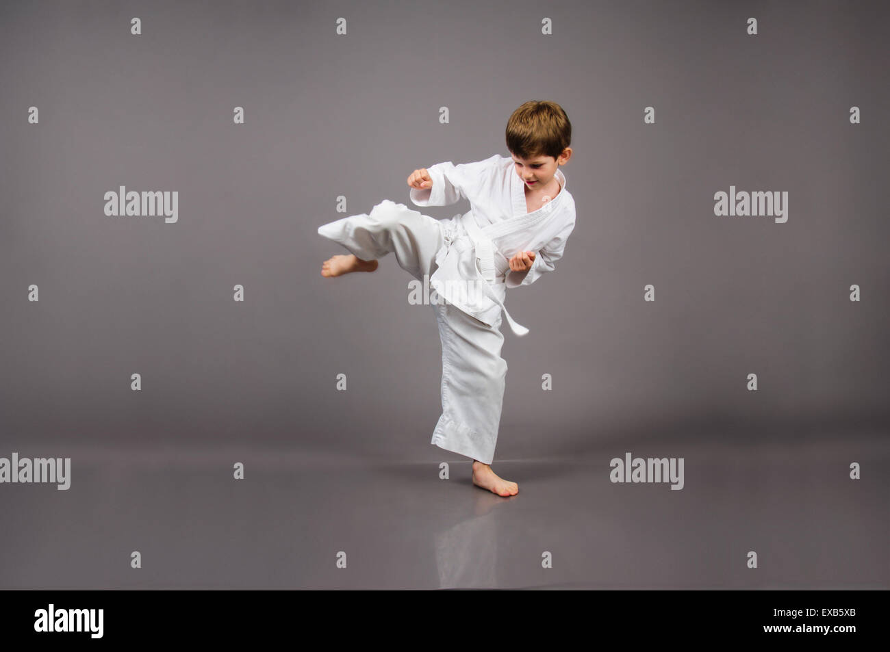 Karate-junge im weißen Kimono Studioportrait auf grauem Hintergrund Stockfoto