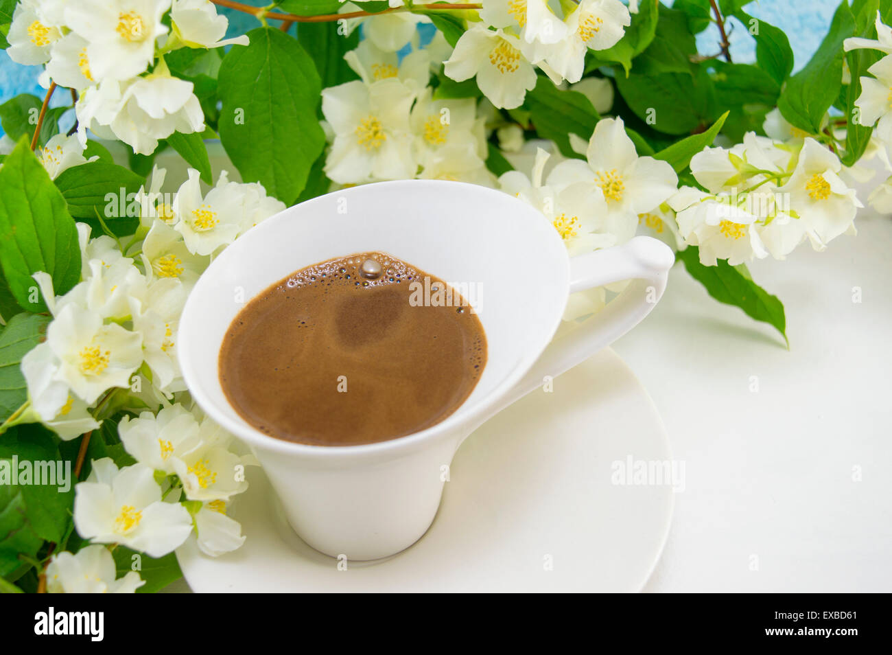 Weiße Tasse Kaffee auf einem Holztisch mit Blumen geschmückt Stockfoto