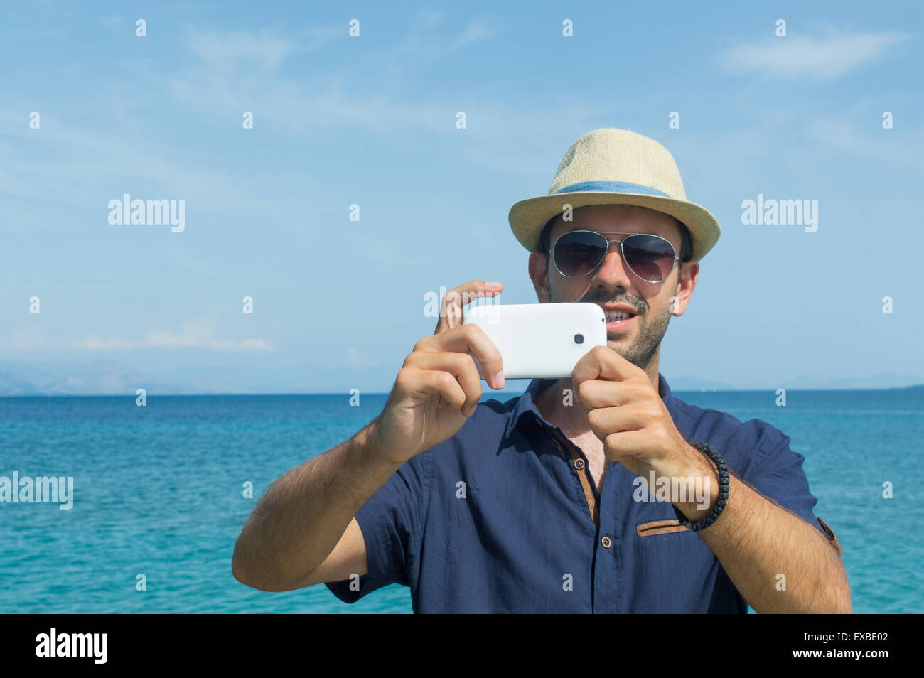 Mann, die Fotos mit seinem Handy am Meer Stockfoto