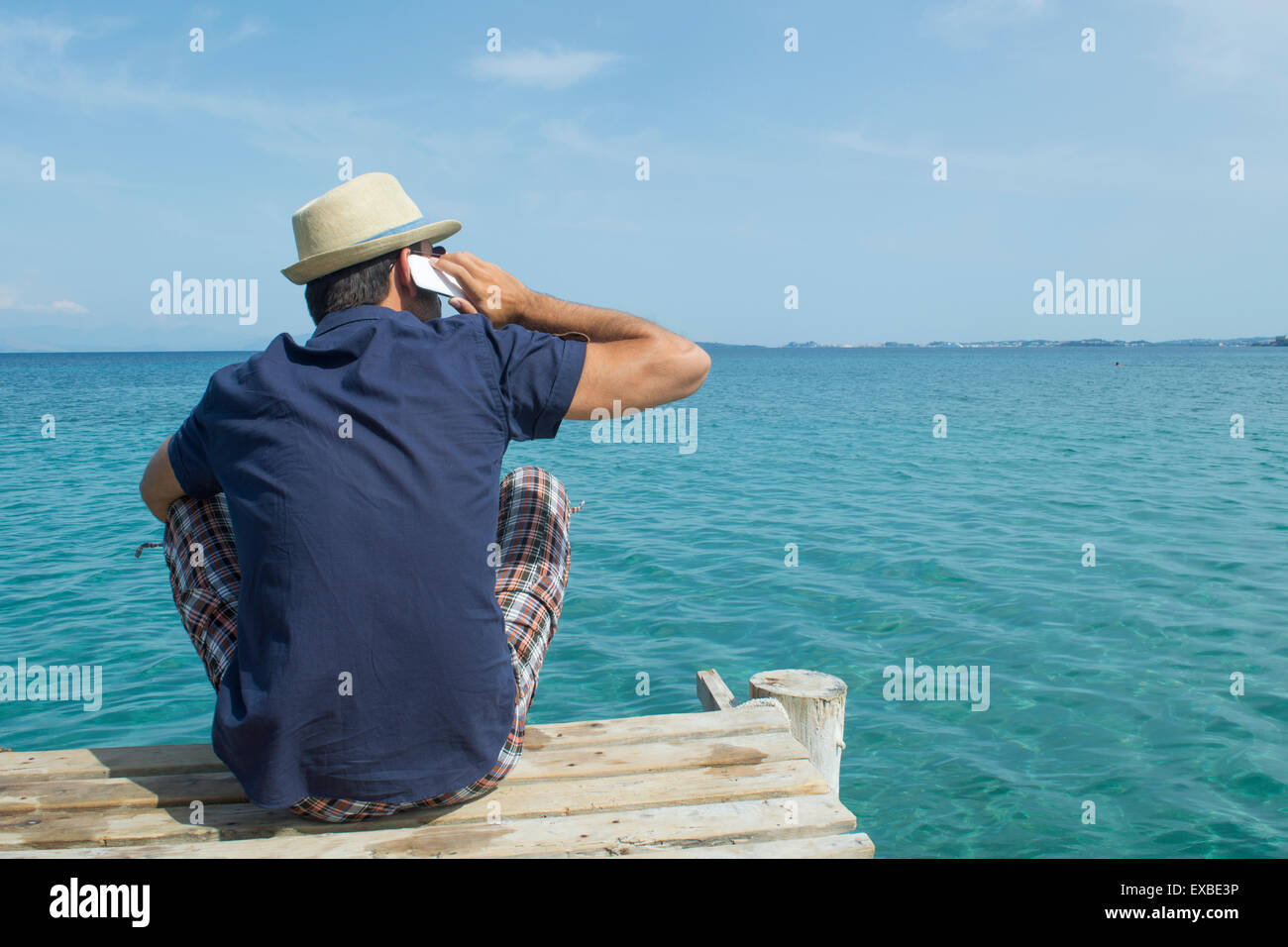 Mann auf seinem Handy an der Anlegestelle auf dem Meer Stockfoto