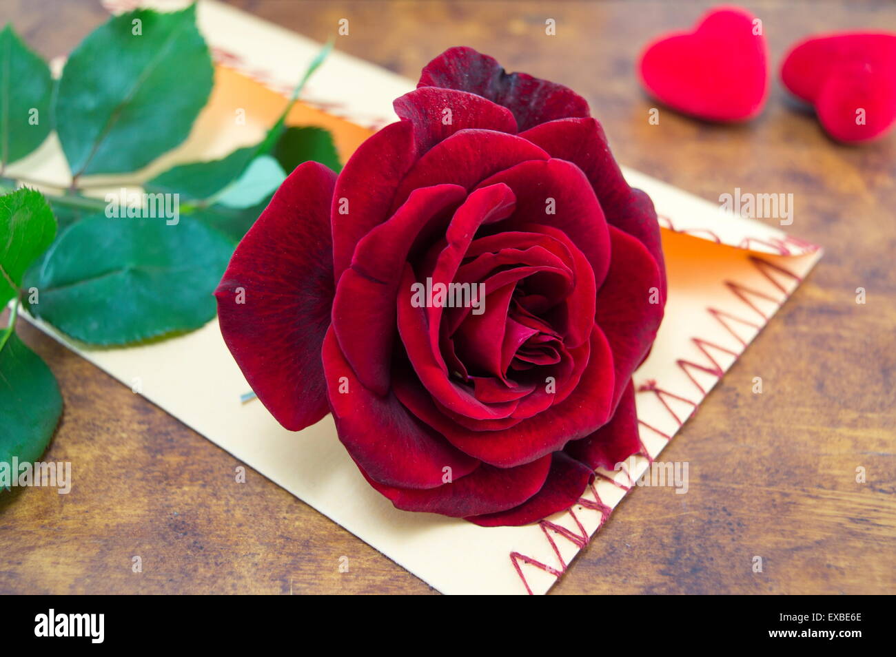 Rose und einen handgemachten Liebesbrief auf einem Tisch mit Herzen verziert Stockfoto