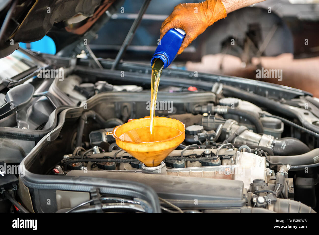 Mechaniker Nachfüllen des Öls in einem Auto Gießen einen Pint Öl durch einen Trichter in den Motor Nahaufnahme von seiner Hand und das Öl Stockfoto