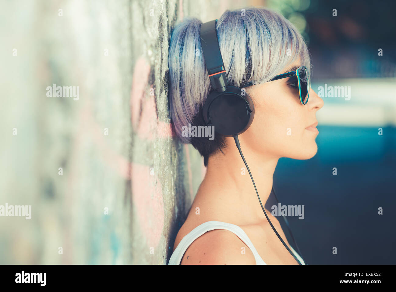 junge schöne kurze blaue Haare Hipster Frau mit Kopfhörern Musik in der Stadt Stockfoto