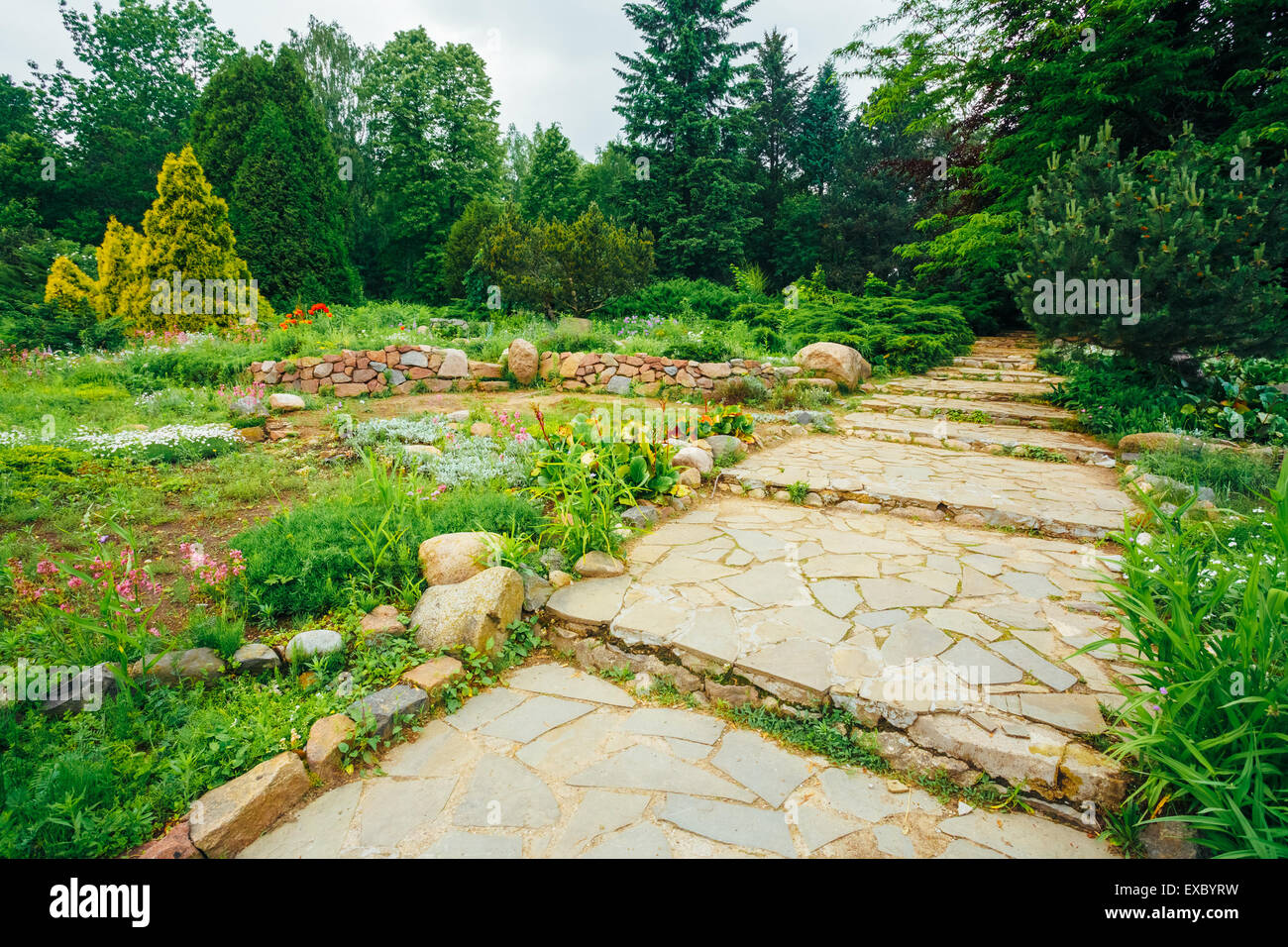 Pathway Gehweg Lane Pflasterweg mit grünen Bäumen und Büschen im Garten. Schöne Allee im Park Stockfoto