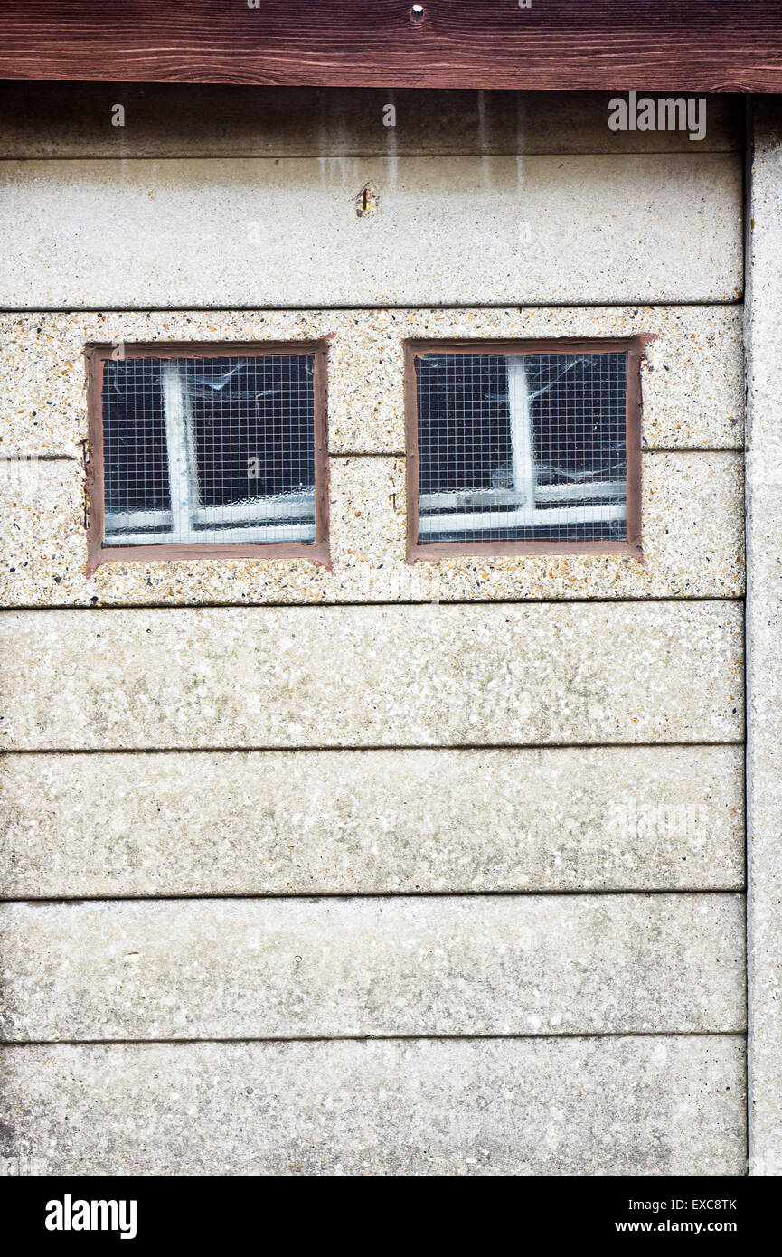 zwei kleine quadratische Fenster in einer Steinmauer Stockfoto
