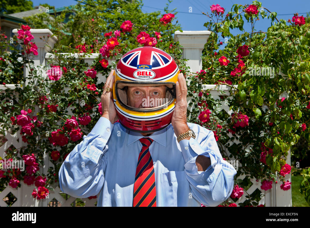 Ein Mann trug ein blaues Kleid Hemd und eine rote Krawatte trägt ein Rennfahrer Helm. Stockfoto