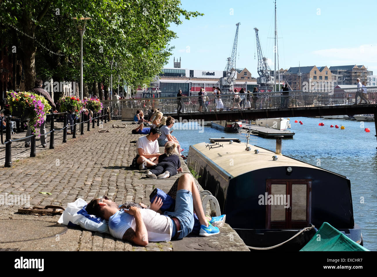 Menschen entspannen und genießen die Sonne an der Hafenpromenade in Bristol, Großbritannien Stockfoto