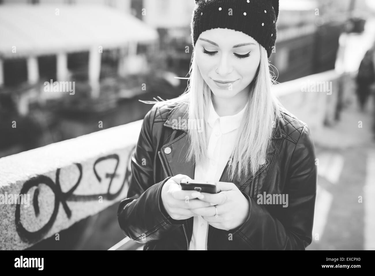 junge schöne blonde glatte Haare Frau in der Stadt mit Smartphone online Internet verbunden Stockfoto
