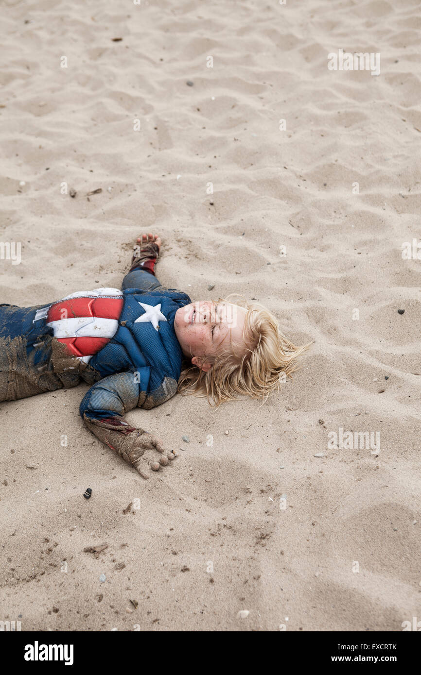 Ein vier Jahre alter Junge in einem Captain America Kostüm spielt an einem Sandstrand am Lake Michigan. Stockfoto