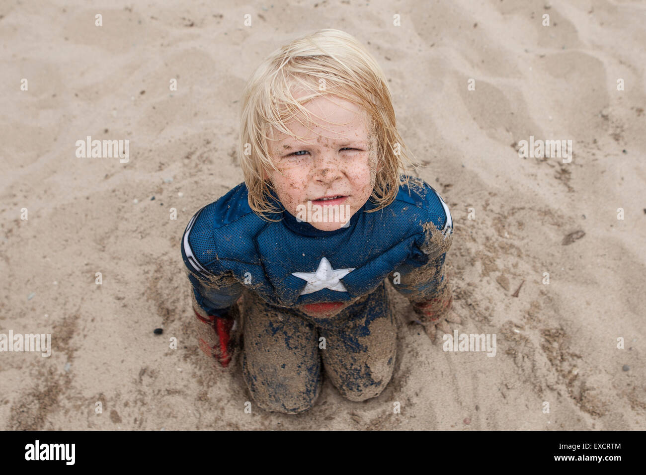 Ein vier Jahre alter Junge in einem Captain America Kostüm spielt an einem Sandstrand am Lake Michigan. Stockfoto