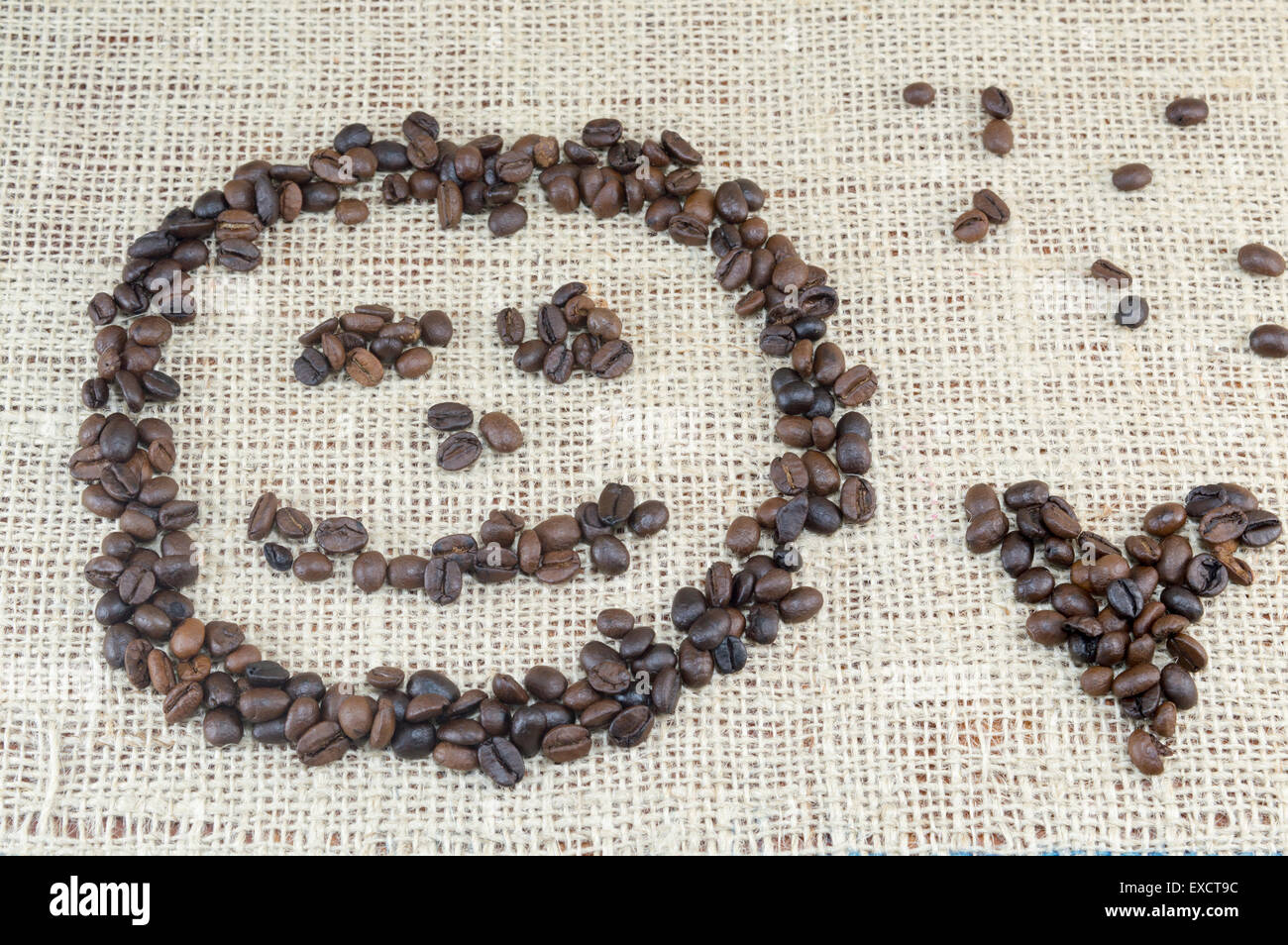 Smiley-Gesicht und Herz-Form gebildet vollständig aus Kaffeekörner auf Kaffee Tasche Textur gelegt Stockfoto