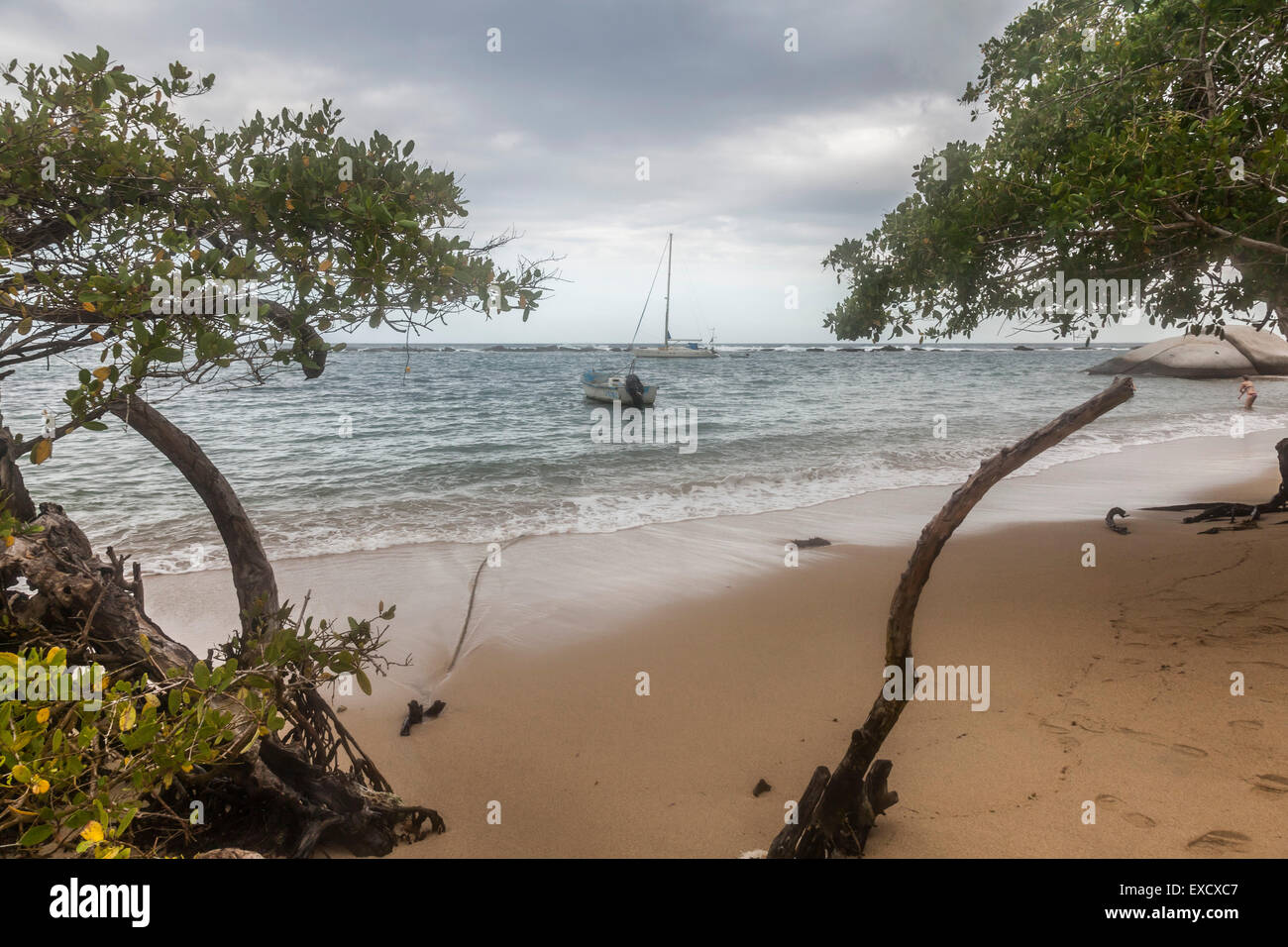 Segelboot und Fischerboot hinter dem Schutzwall aus einem felsigen Riff im Tayrona National Park in der Nähe von Santa Marta, Colombi verankert Stockfoto